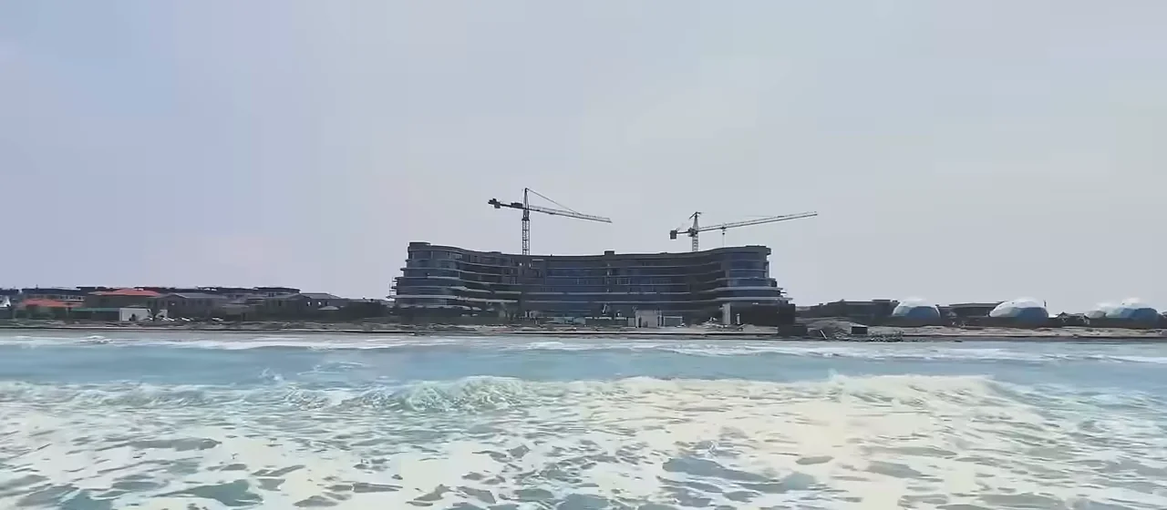 Skyline с моря, май 2025: низкий длинный корпус над пляжем и два крана